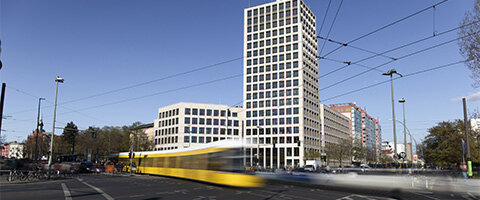 Stefan-Haym-Platz mit Blick auf den neuen Büroturm; im Vordergrund fährt eine Straßenbahn vorbei © HOWOGE Lydia Hesse