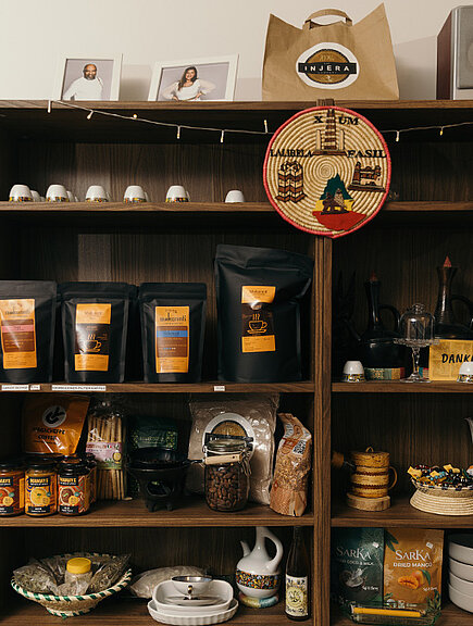 Ein Foto eines offenen Schrankes mit Kaffeepackungen, Dosen und Geschirr.