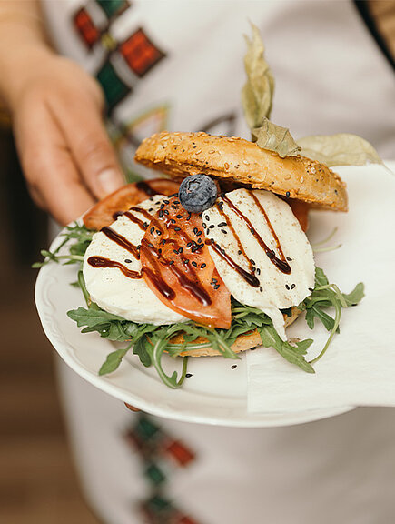 Ein Foto eines Bagels mit Mozzarella, Tomaten und Rucola auf einem Teller