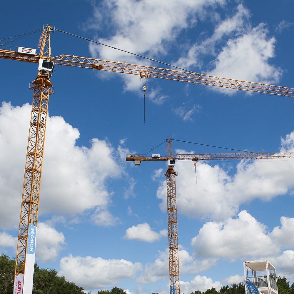 Baukräne aus der Froschperspektive vor blauem Himmel