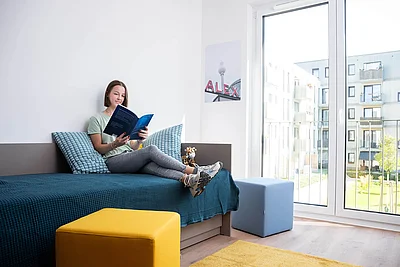 Eine junge Frau sitzt auf einem Bett und liest