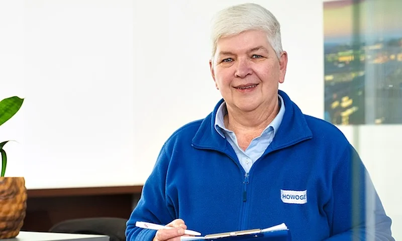 Eine Frau mit grauen kurzen Haaren in einem blauen HOWOGE Pullover steht an einem Schalter