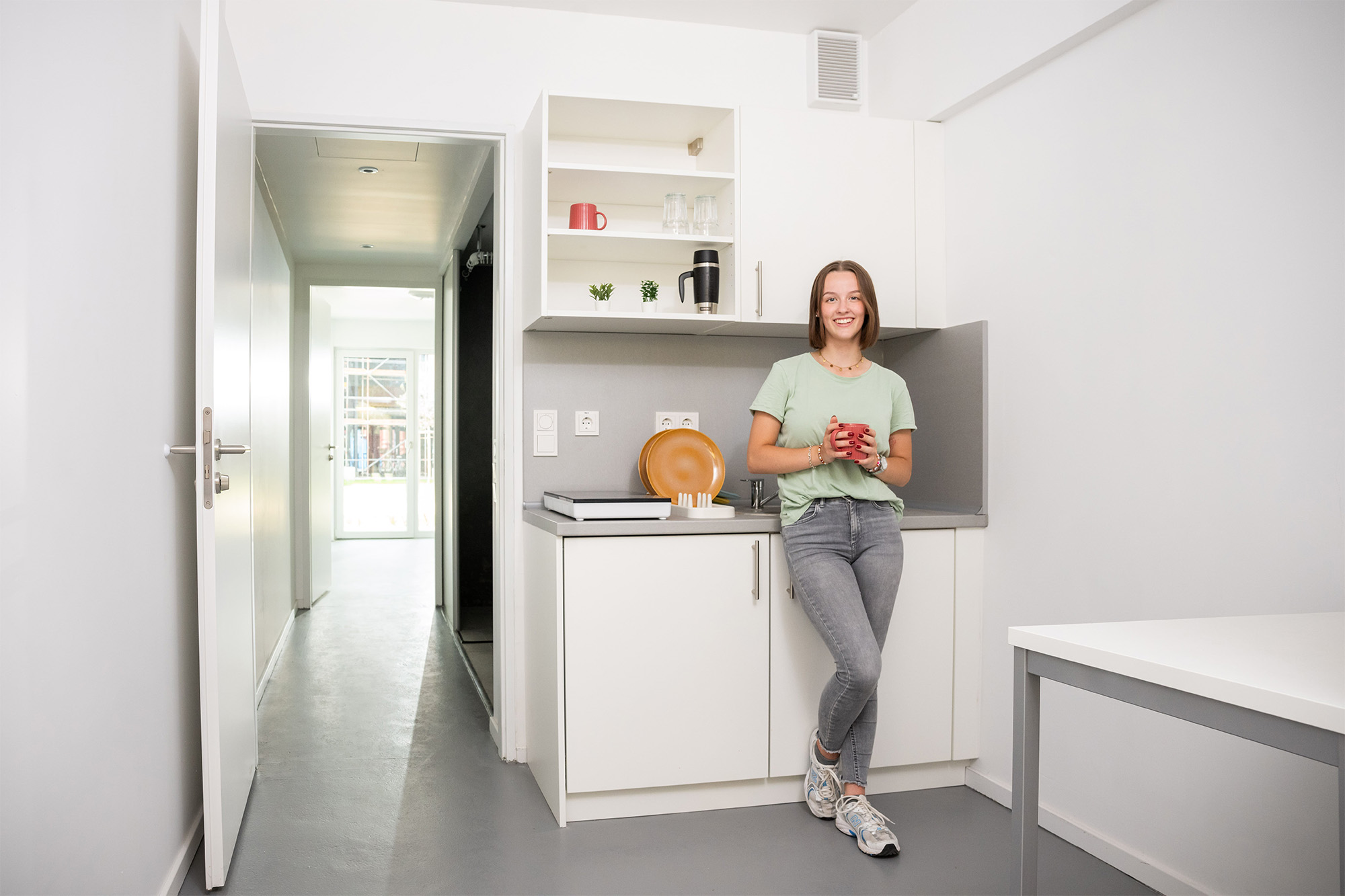 Eine Frau lehnt in der Küche an der Arbeitsplatte.