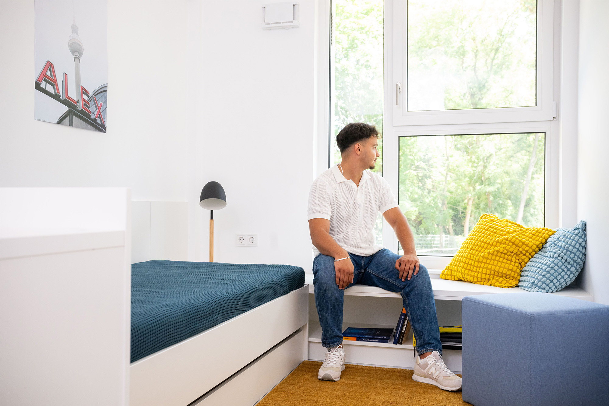 Ein Mann sitzt in einem Schlafzimmer neben dem Bett.