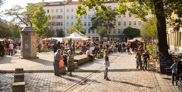 Ein Platz voll mit Menschen, in einem Berliner Kiez.