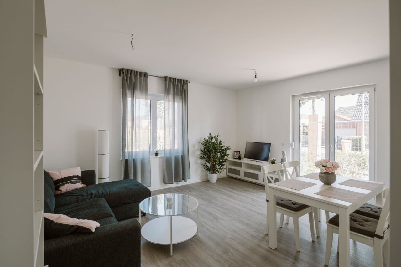 Bild – Ein eingerichtetes Wohnzimmer mit Couch, Fernseher und Esstisch