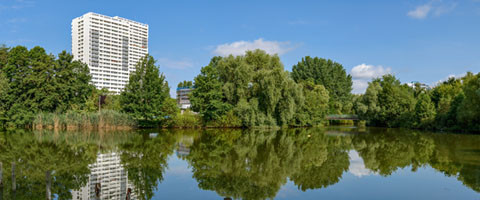 Ein Hochhaus hinter einem See in Fennpfuhl.