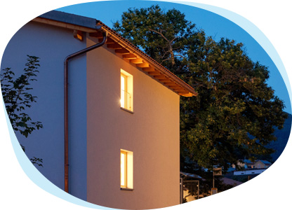 Ein Einfamilienhaus mit beleuchteten Fenstern an einem Abend. 