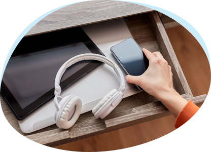 Laptop, Kopfhörer und Smartphone werden in einer Schublade vor fremden Blicken versteckt. 