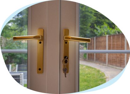 Eine Doppelflügeltür einer Terrasse mit Blick in den Garten. Im Schloss steckt ein Schlüssel.