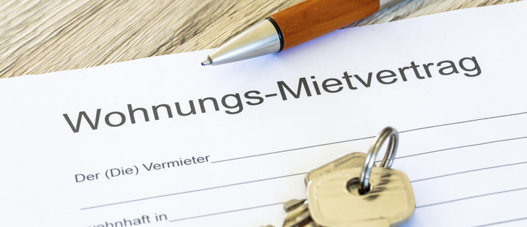 Apartment rental agreement, key and pen lie on a table.