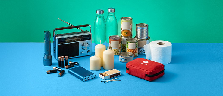 Ein Foto mit Basis-Notfallprodukten wie Kerzen, Wasserflaschen, Erste-Hilfe-Set, Konserven usw.