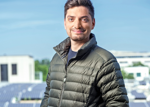 Ein Mann steht auf dem Dach. Im Hintergrund ist eine Solaranlage